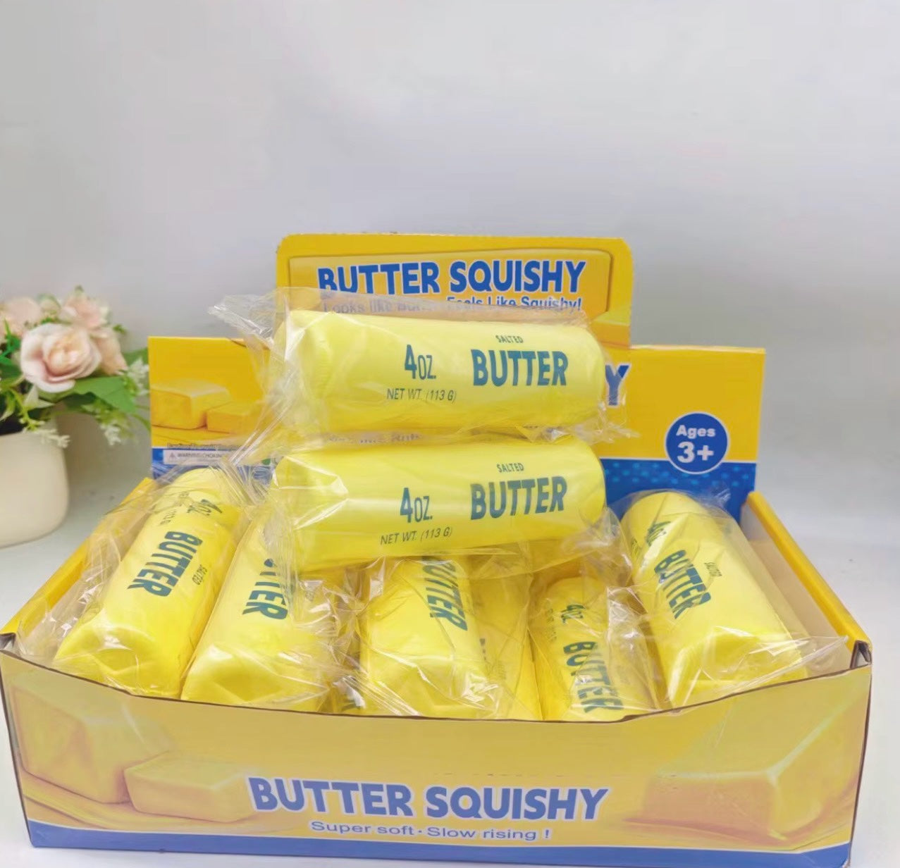 SquishStudio butter stick shaped slow-rising sensory toys in yellow packaging displayed in a retail box