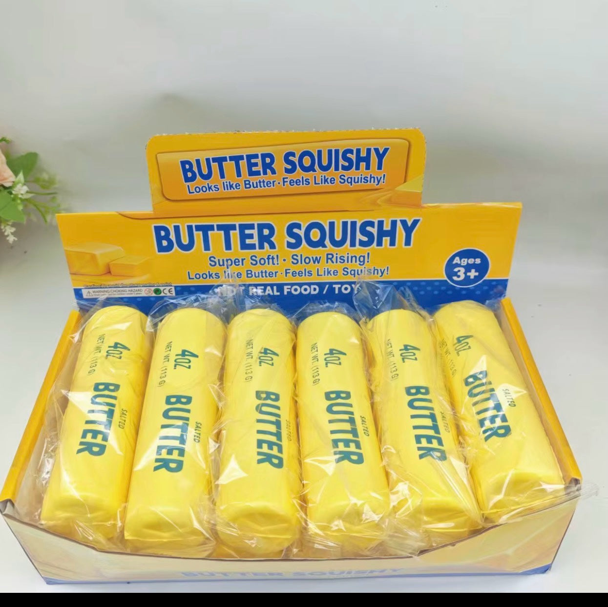 SquishStudio butter stick sensory toys in a retail display box, featuring yellow slow-rising squishy butter sticks.